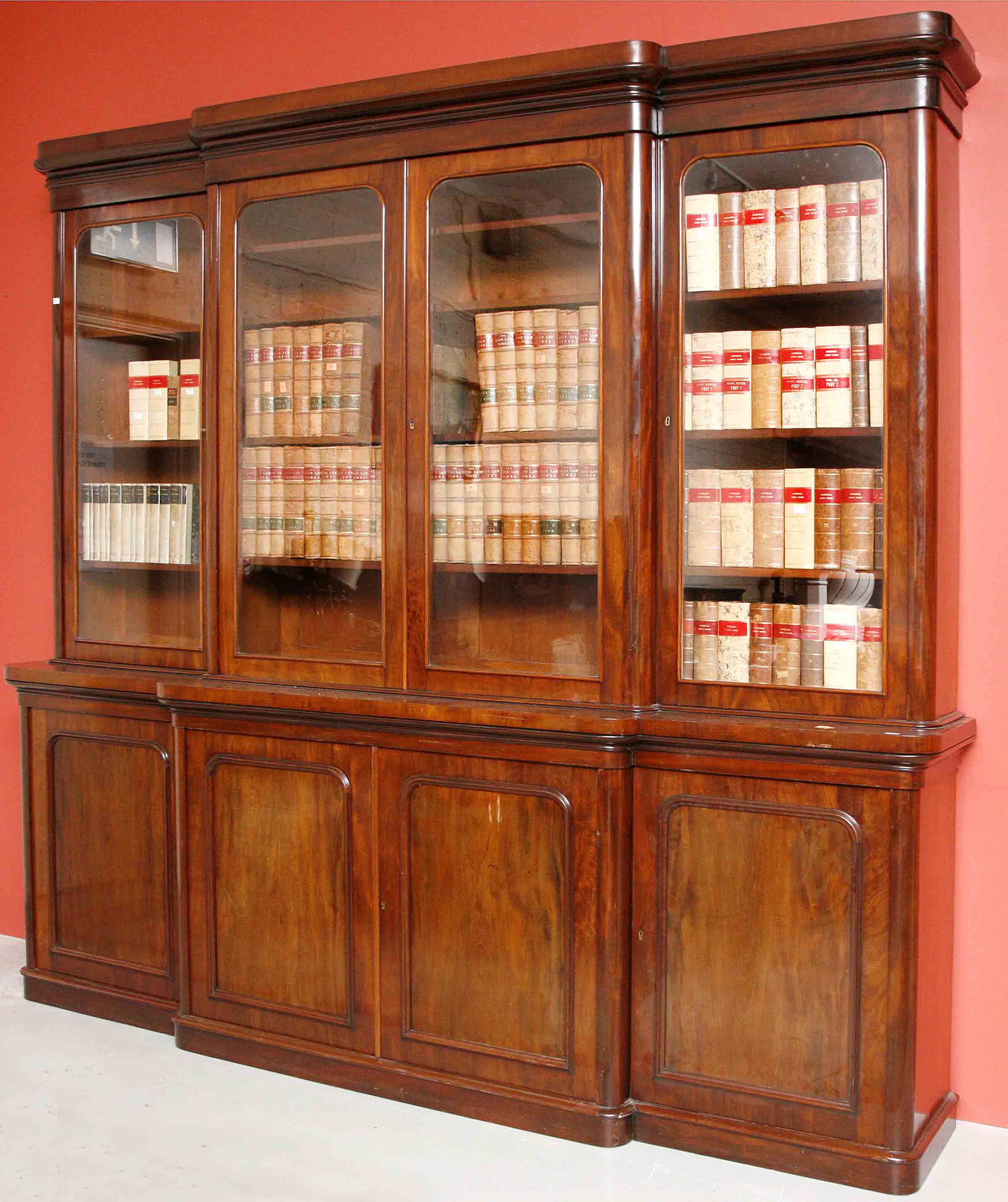 AN ATTRACTIVE VICTORIAN MAHOGANY BOOKCASE,
the moulded cornice above four glazed doors, on a base