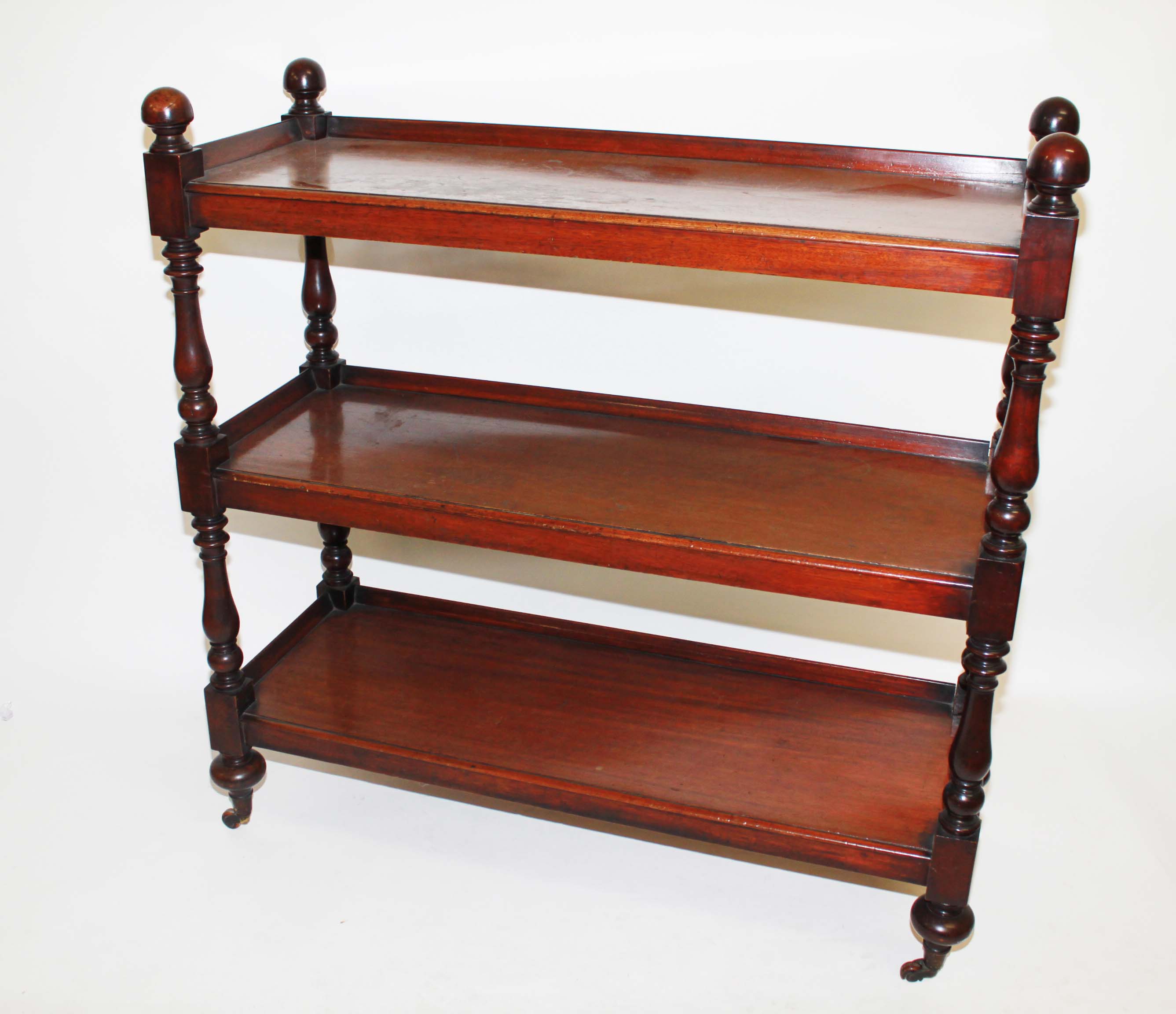 A MAHOGANY THREE-TIER DUMB WAITER, 
mid-19th century, on baluster turned supports and bun feet, 49in