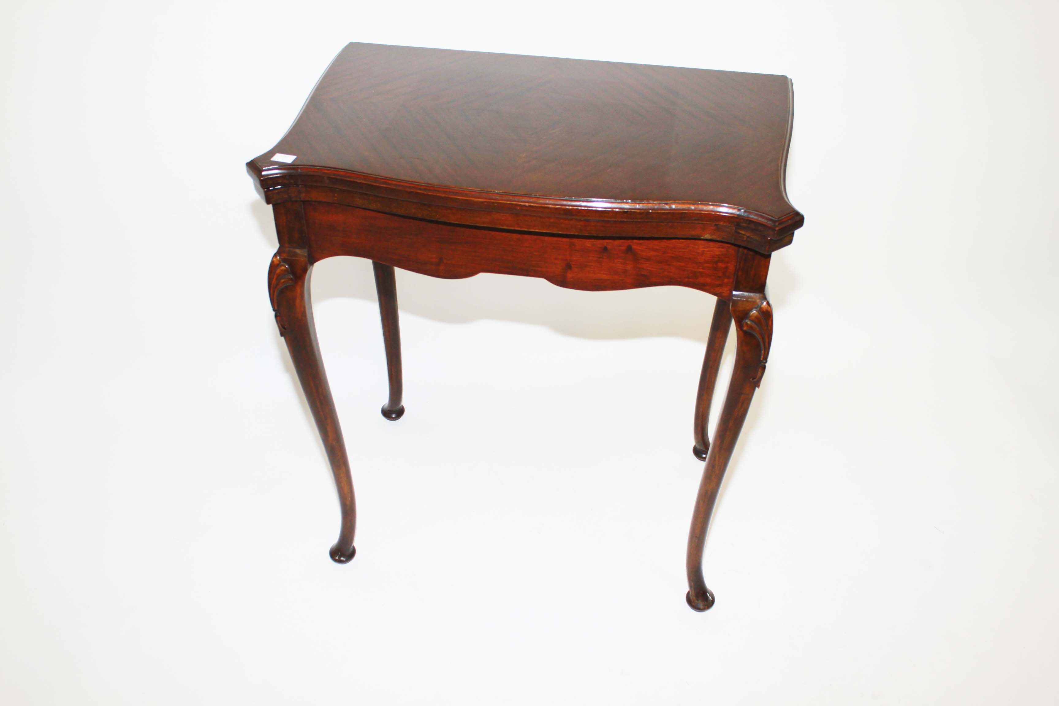 A Serpentine Shaped Fold Over mahogany card table,
20th Century, with moulded top, on shell carved