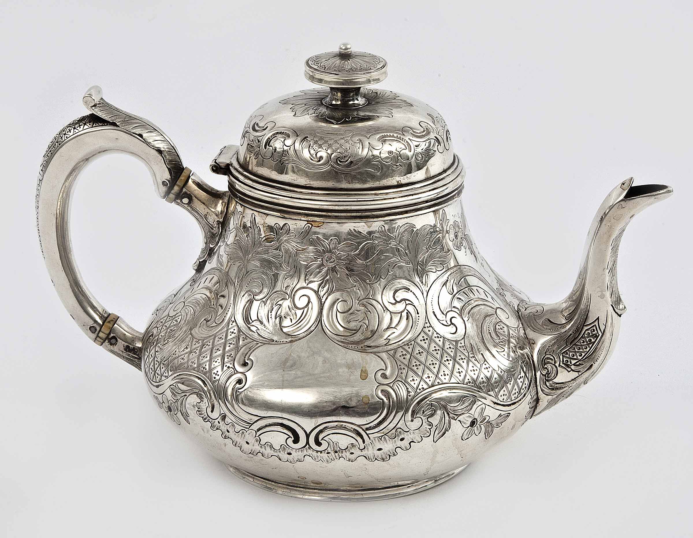 AN IRISH VICTORIAN SILVER TEAPOT, by R.S. Dublin 1858, chased with ornate scrolls, foliage and