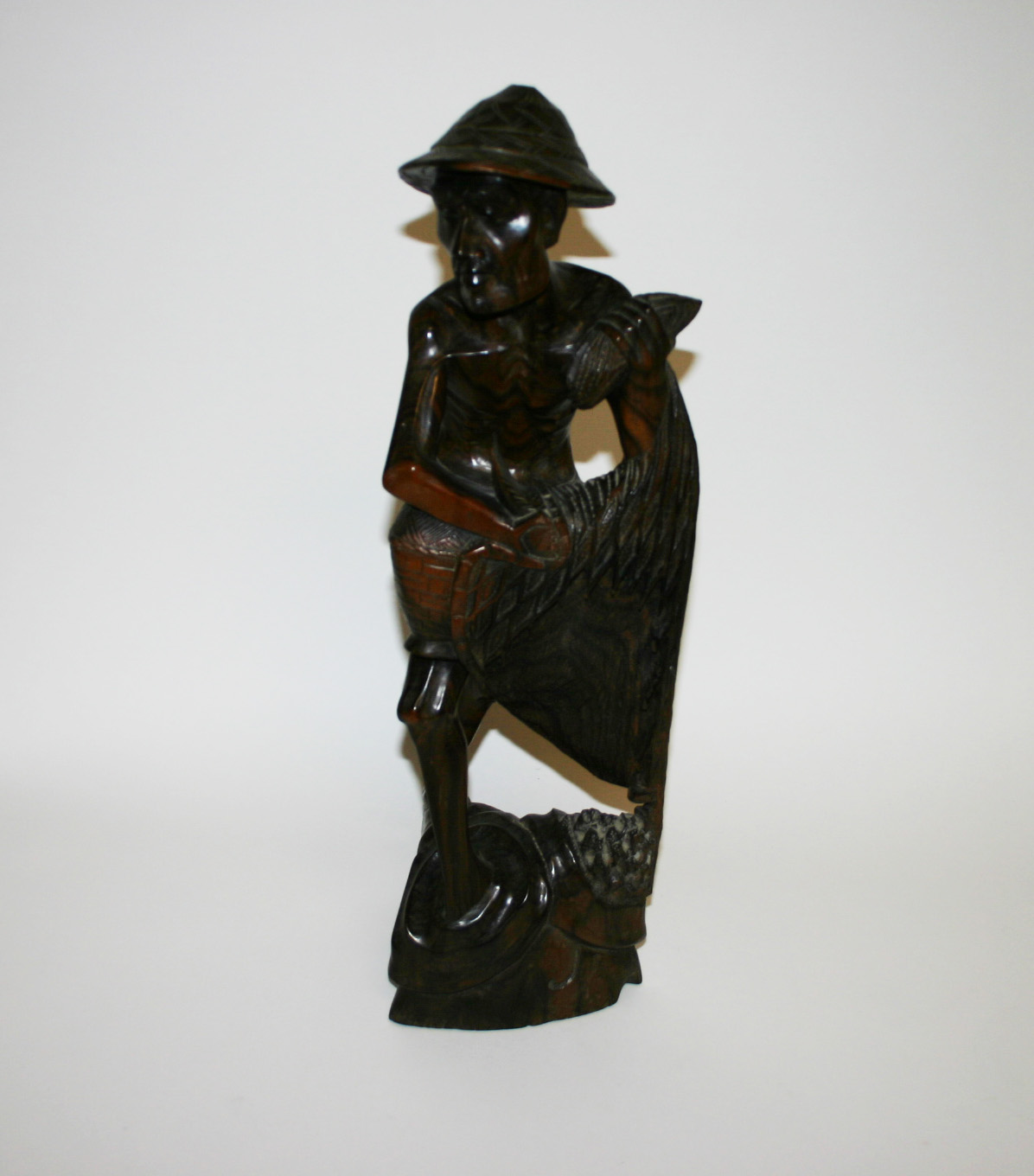 A CARVED CHINESE HARDWOOD GROUP, modelled with a peasant fisherman retrieving fish from a net,