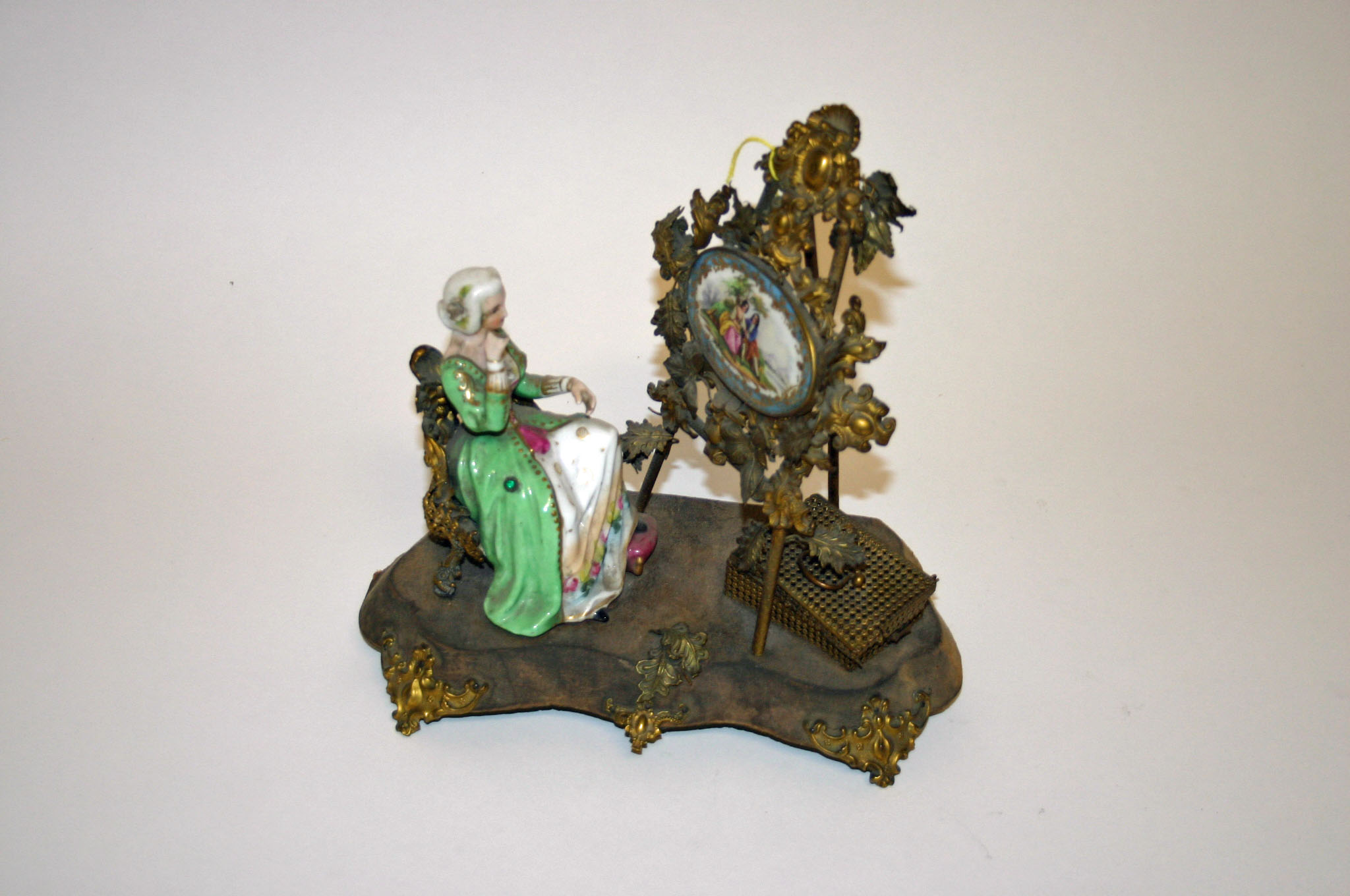 AN UNUSUAL EMBOSSED BRASS AND GILT METAL GROUP, in the Sevres style, modelled with lady seated in