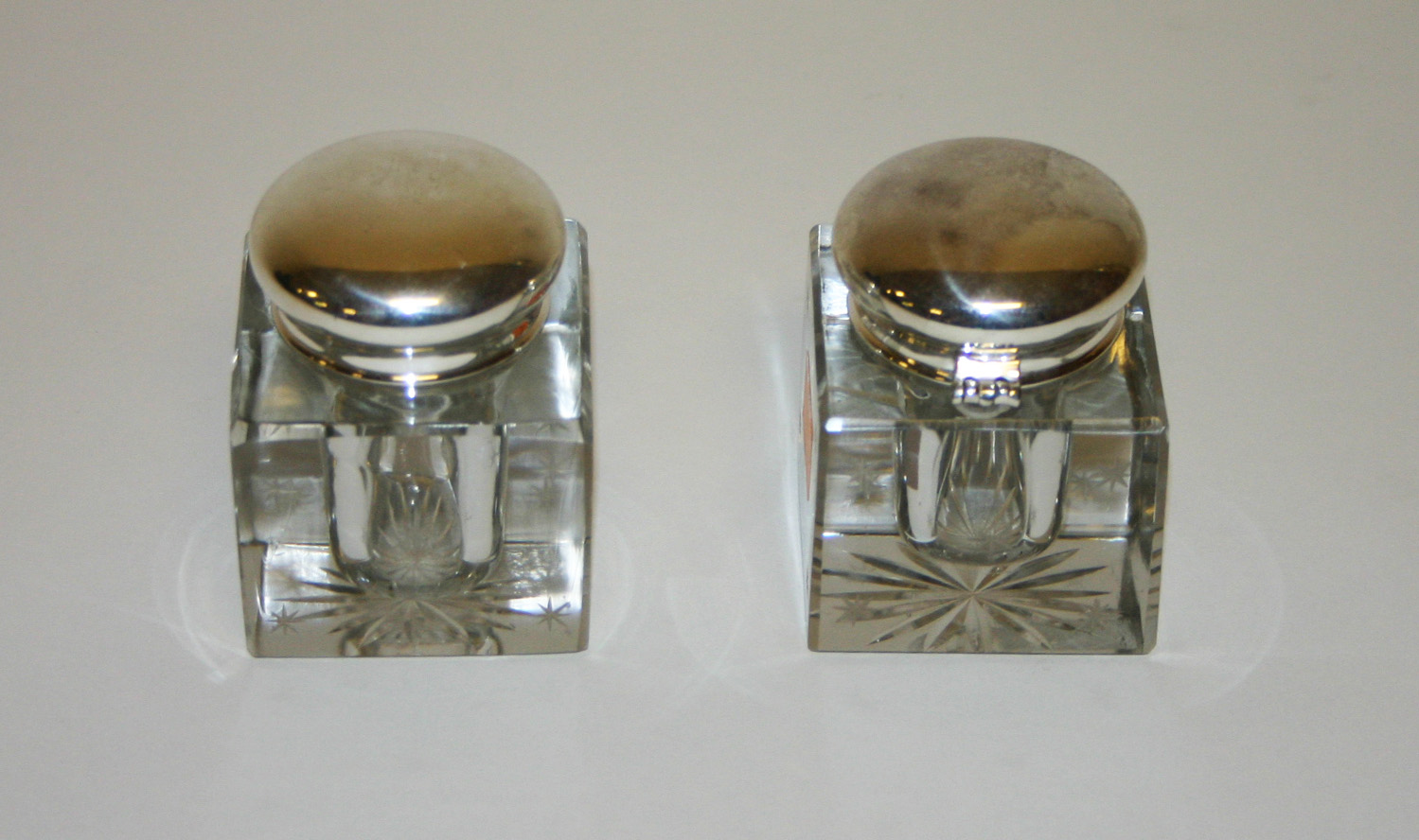 A PAIR OF STAR CUT SQUARE GLASS INK POTS, each with silver plated mounts and cover, 2.5in (6.