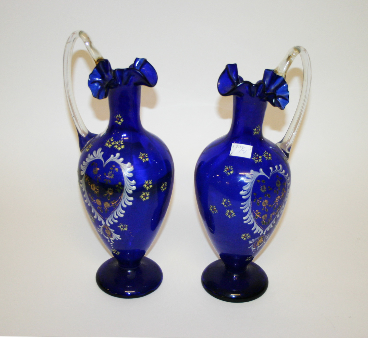 A PAIR OF BLUE GLASS AND ENAMEL DECORATED EWERS OR VASES, early 20th century, each of baluster