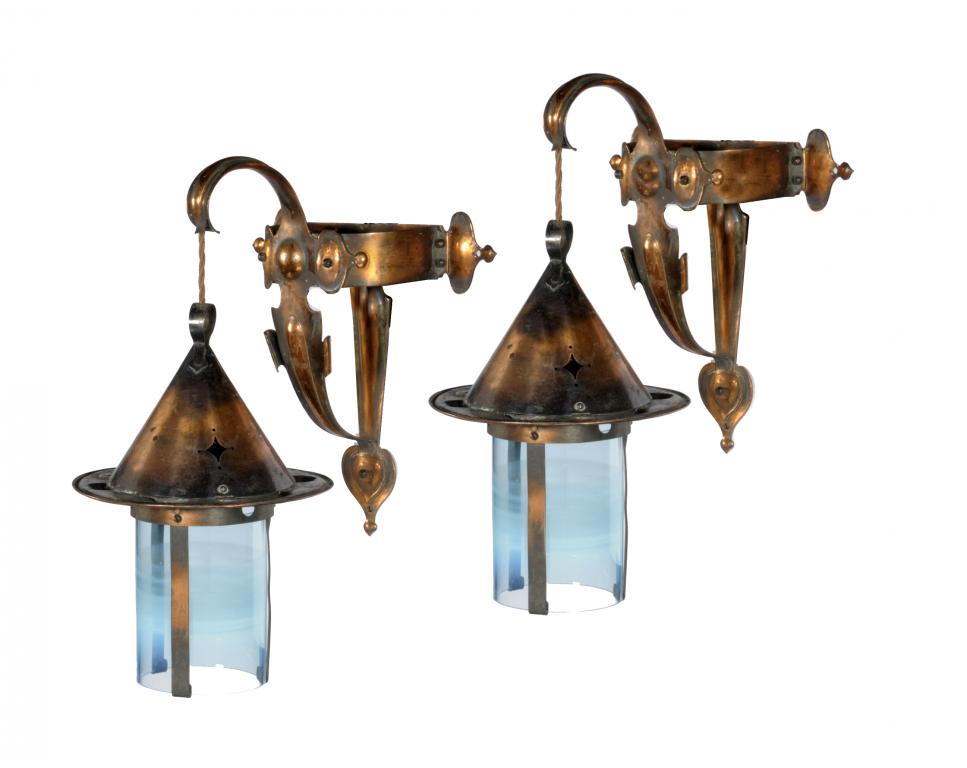 A PAIR OF ARTS & CRAFTS COPPER WALL LANTERNS with conical vent and suspended from the scrolling