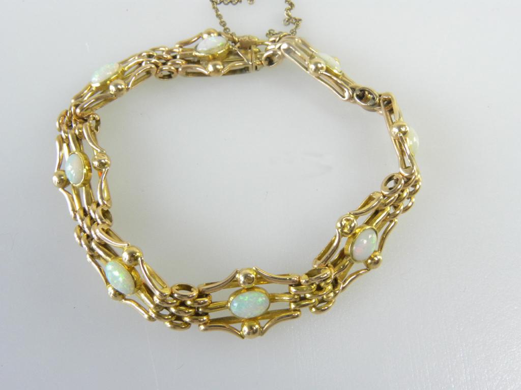 A GOLD BRACELET OF EIGHT SECTIONS EACH CENTRED BY AN OPAL CABOCHON IN GOLD MARKED ON TONGUE 15,