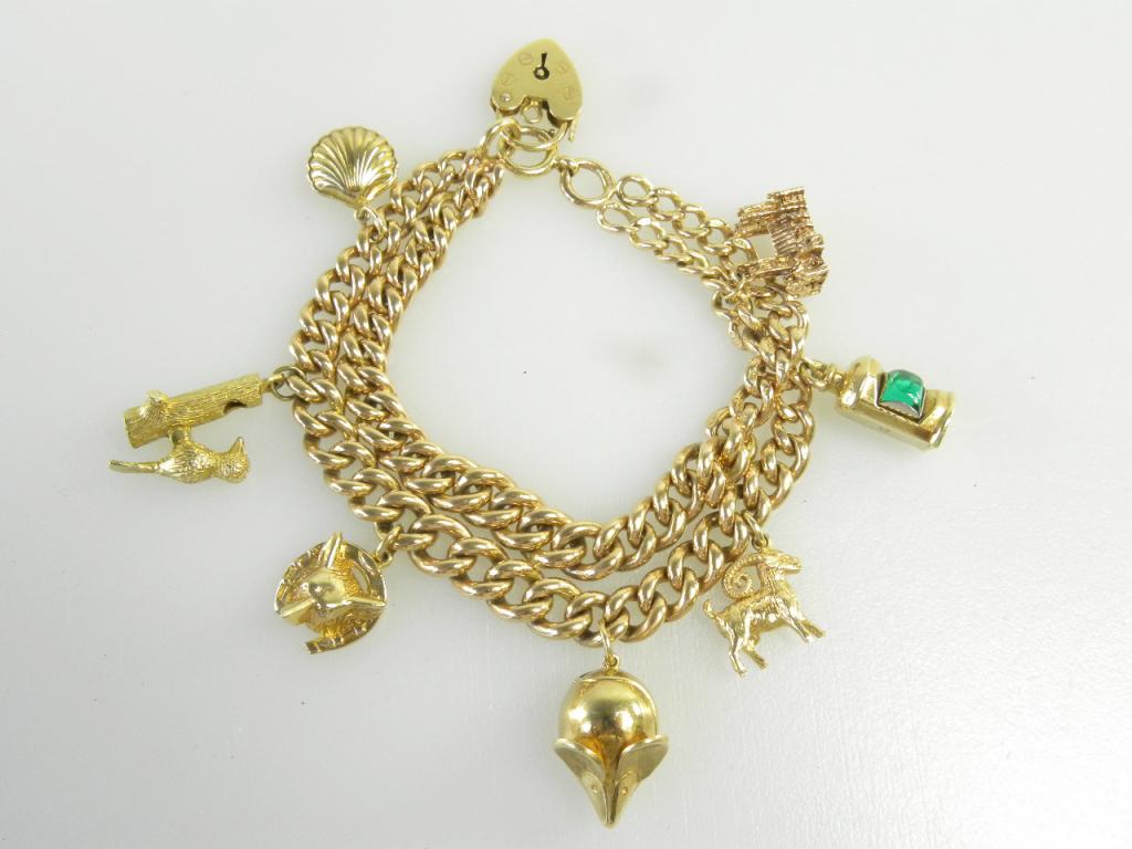 A 9CT GOLD CHARM BRACELET ADAPTED FROM AN ALBERT AND HUNG WITH VARIOUS GOLD CHARMS, 55G