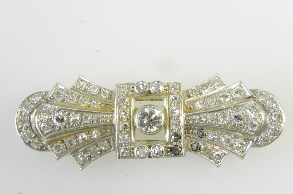 A DIAMOND BROOCH WITH LARGER CENTRAL DIAMOND COLLET IN WHITE GOLD SEVERAL SMALLER DIAMONDS