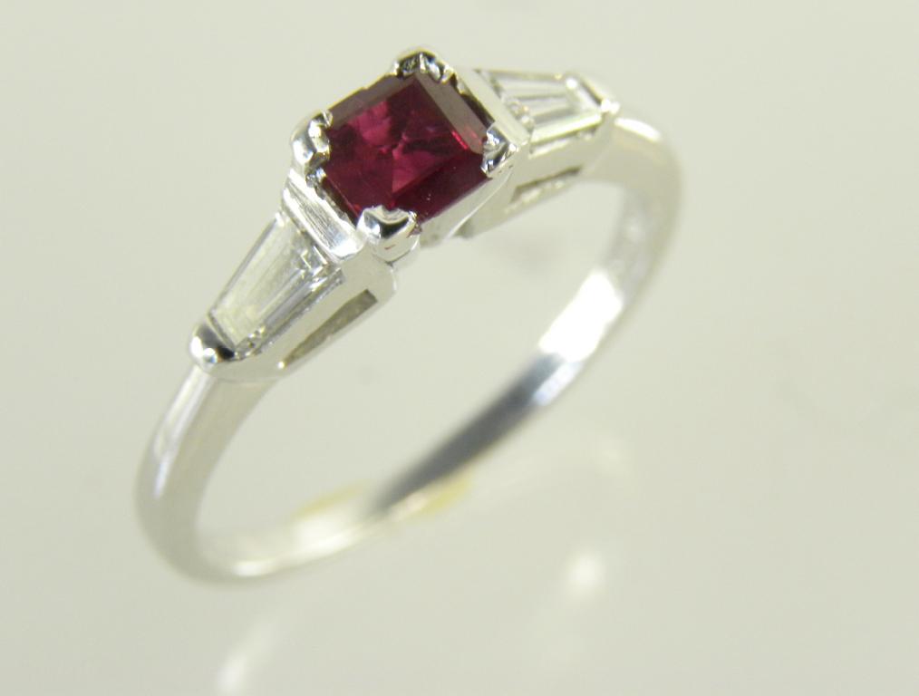 A RUBY AND DIAMOND RING WITH STEP CUT RUBY AND TRAPEZE DIAMOND SET SHOULDERS IN WHITE GOLD MARKED