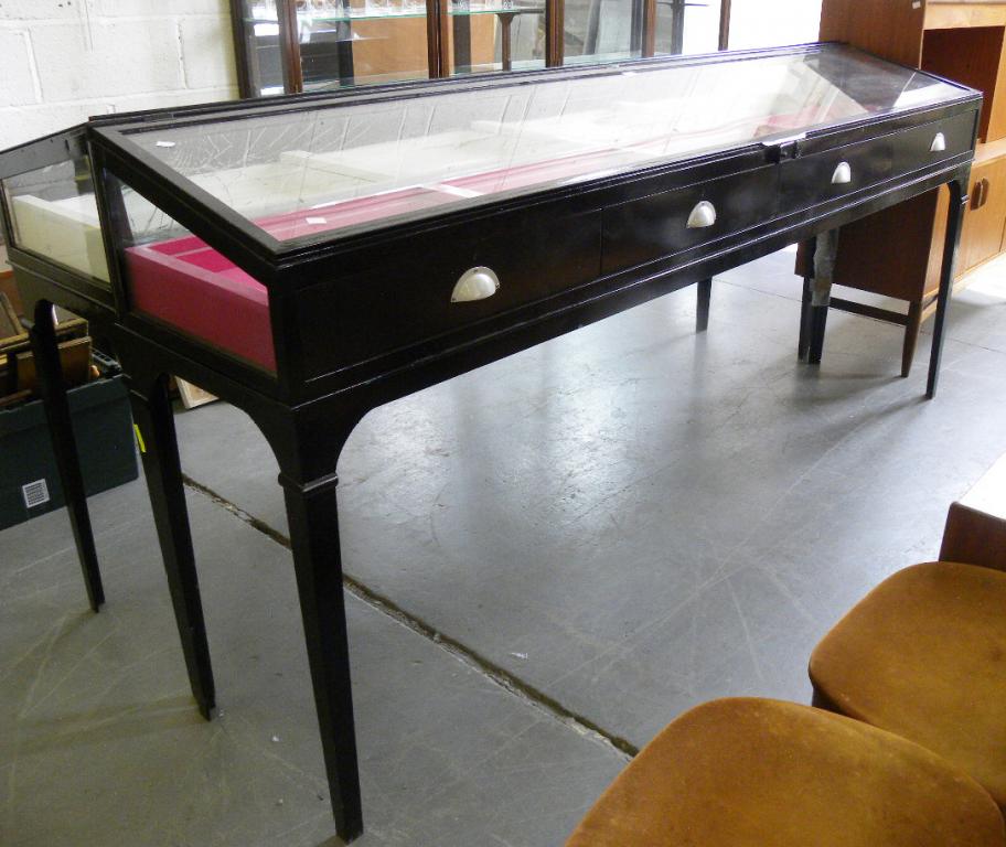 A PAIR OF BLACK PAINTED METAL JEWELLERY DISPLAY TABLES WITH SLOPING LID, FOUR DRAWER FRONT AND