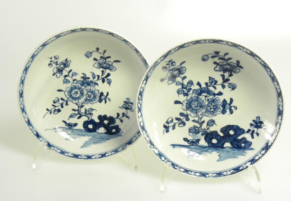 A PAIR OF LOWESTOFT SAUCERS PAINTED IN UNDERGLAZE BLUE WITH FLOWERS GROWING FROM A BLUE HOLLOW ROCK