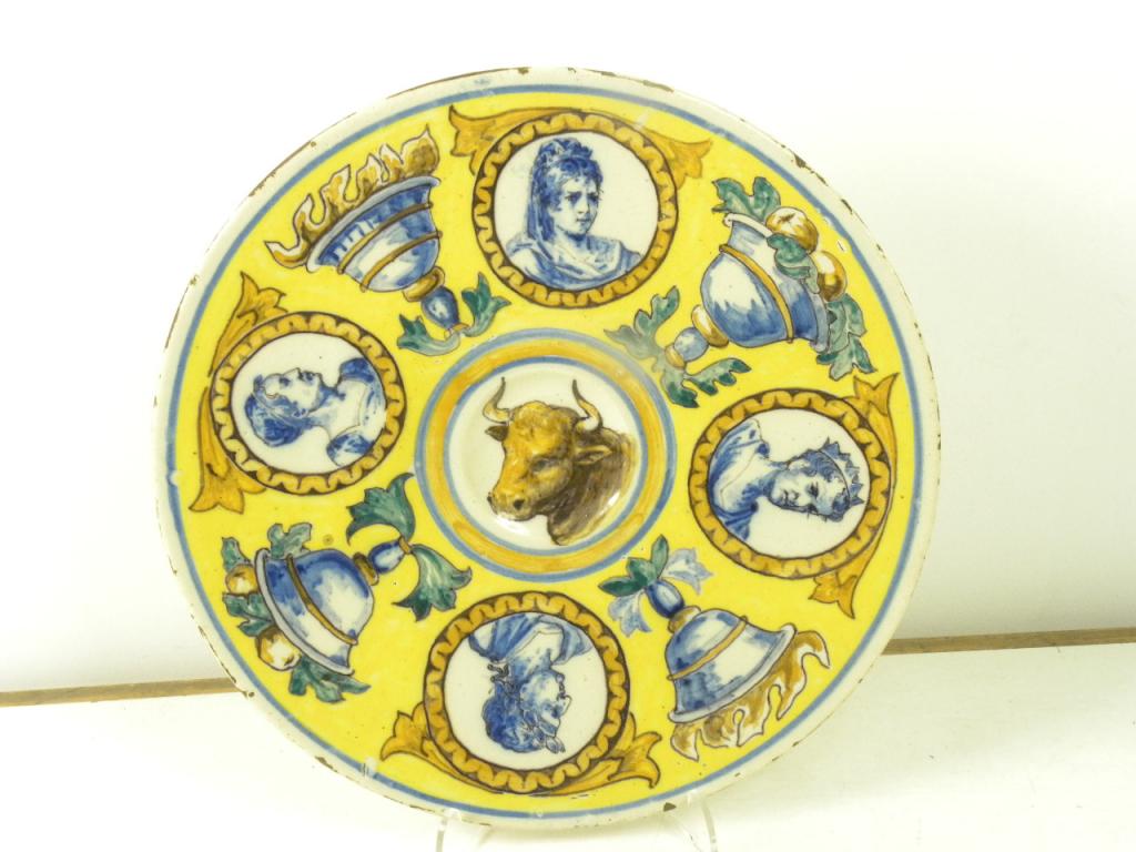A CONTINENTAL YELLOW GROUND TIN GLAZED EARTHENWARE DISH PAINTED WITH THE HEAD OF BULL WITHIN