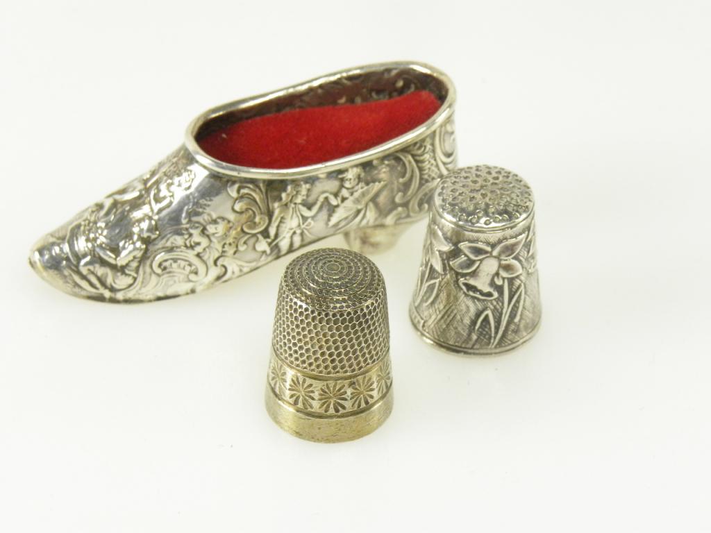 A DUTCH SILVER SHOE NOVELTY PIN CUSHION AND TWO SILVER THIMBLES