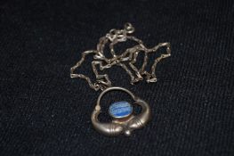 A fish pendant on a silver chain with a blue stone