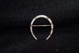 A Gold, White enamel "Horseshoe" and half pearl brooch stamped 14k
