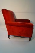 A red upholstered chair on castors