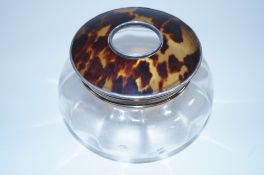 A glass toilet jar with a tortoise shell and silver lid
