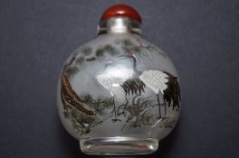 An oriental glass scent bottle with red stopper, decorated with two cranes