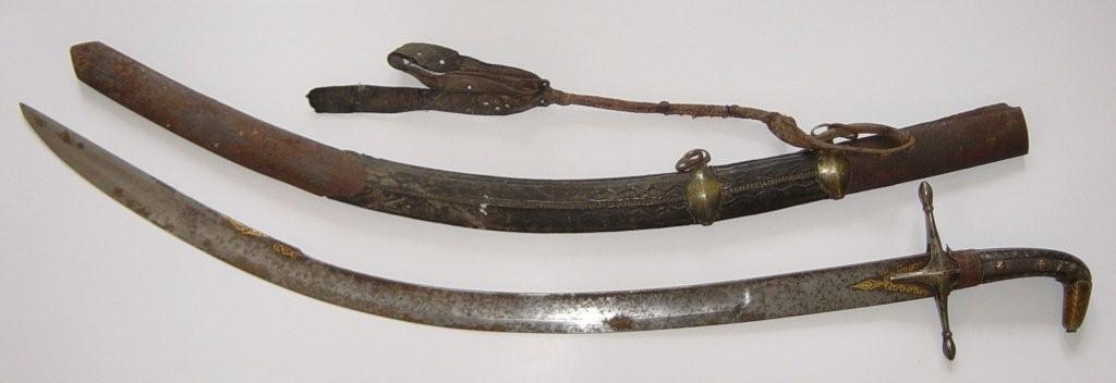 An early 19thC Eastern sabre in scabbard, the horn hilt with metal inlay and down-turned pommel, the