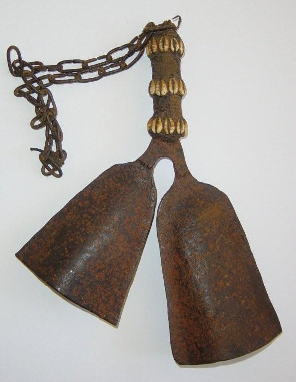 An old African herdsman`s bell, the two flattened iron `bells` emerging from a cloth bound handle