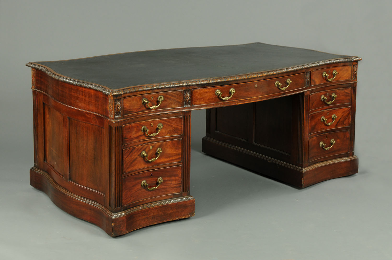 A late Victorian mahogany partners desk, of serpentine outline, the top with tooled leather