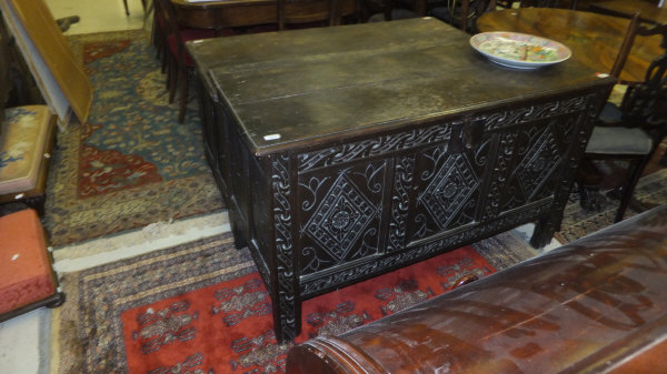 An 18th century oak coffer, the twin planked top with moulded edge over a triple panel carved