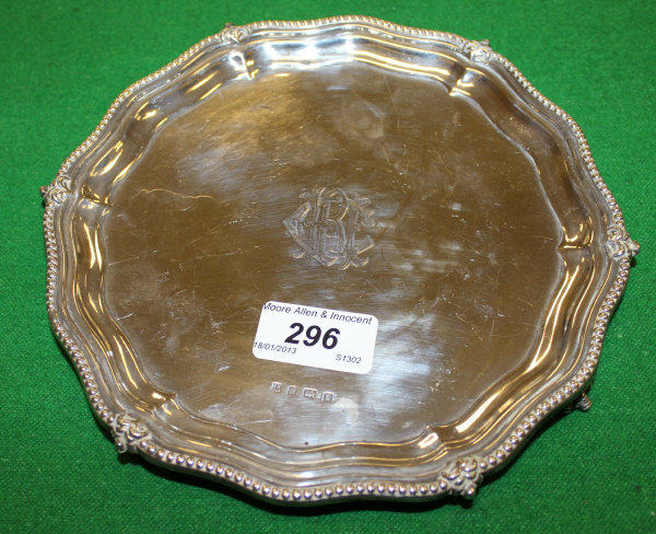 An Edwardian silver card tray with pie crust gadrooned edge raised on three paw and ball and claw