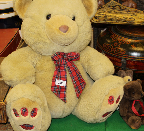 A modern golden plush soft teddy bear toy with tartan scarf, and two miniature brown teddy bears,