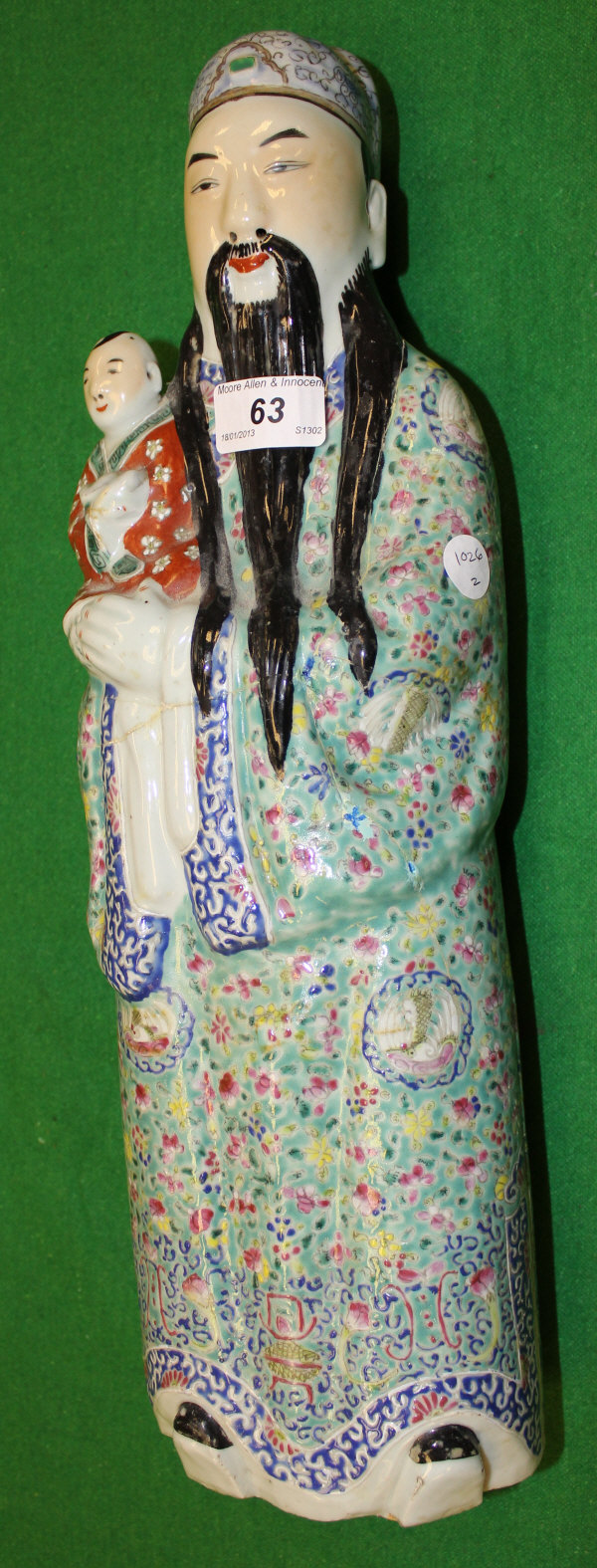 A Chinese pottery figure of a bearded man standing holding a young child in his arms in famille-rose
