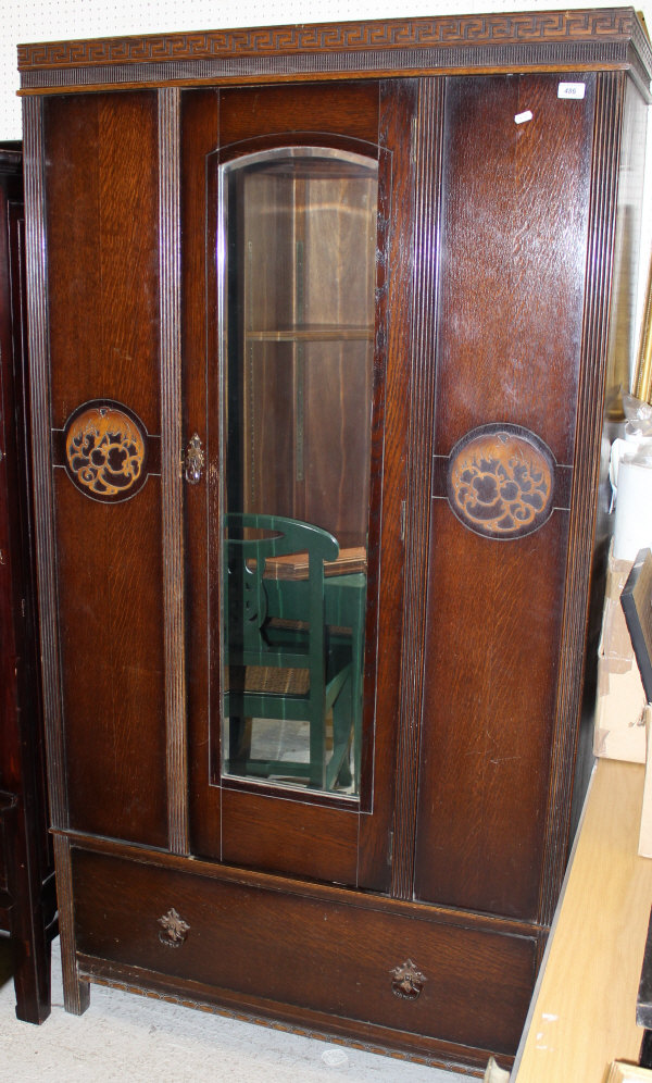 A circa 1930's oak wardrobe, the single mirrored door above a single drawer, raised on block feet