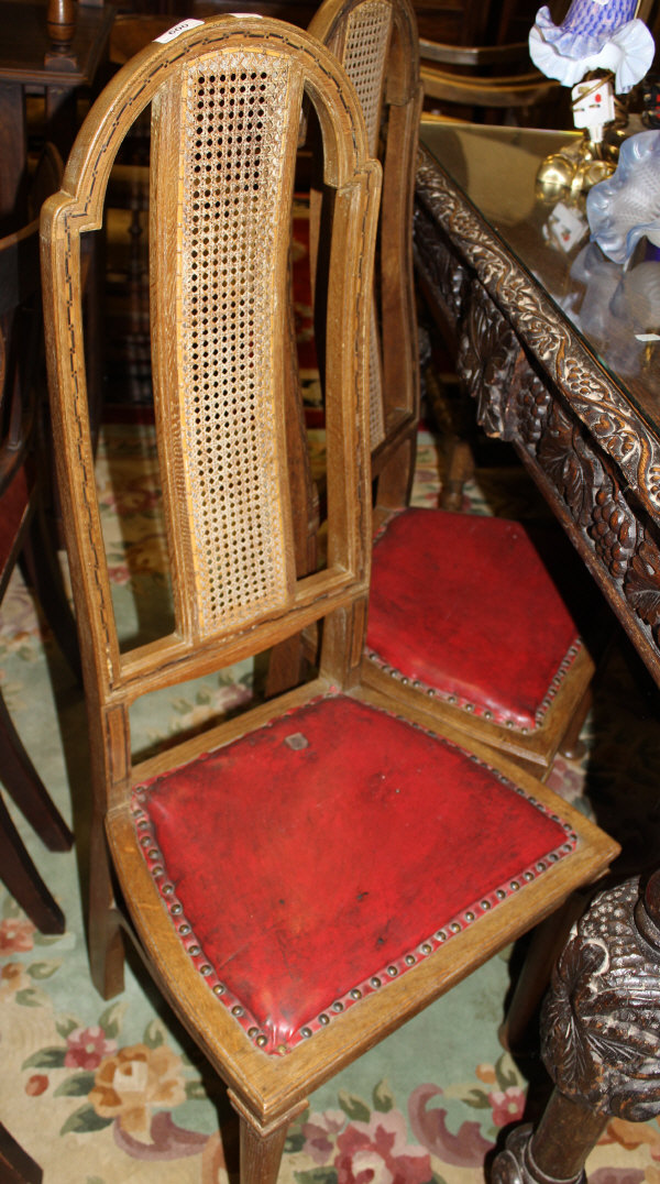 A pair of oak hall chairs in the Flemish taste, the arched backs with inlaid decoration and cane