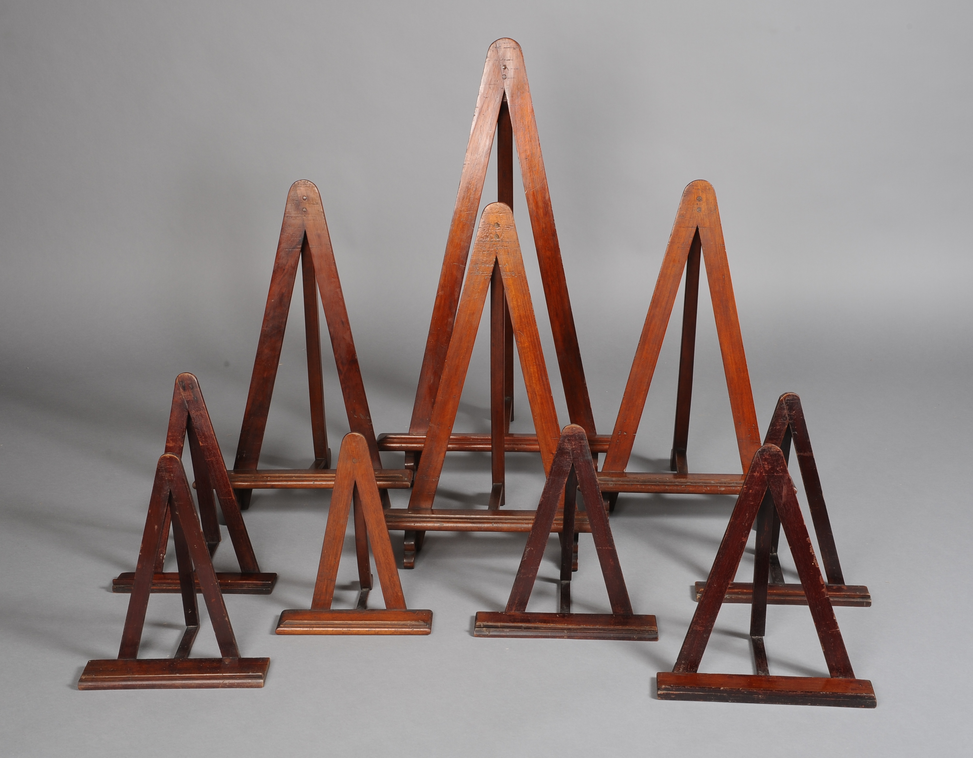 FOUR MAHOGANY STAINED LARGE PICTURE STANDS, of triangular construction, the largest 99cm high,