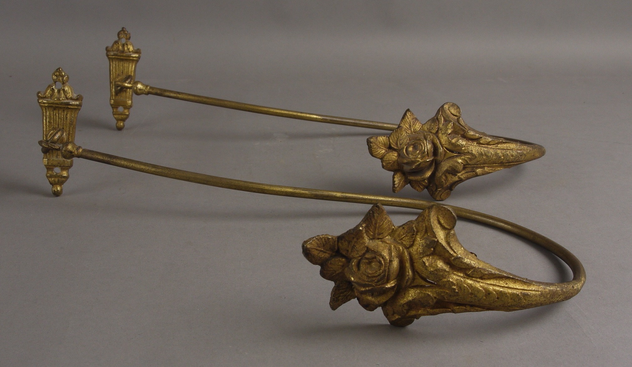 A PAIR OF GILT METAL CURTAIN TIE-BACKS, with flower and scroll terminals, 30cm