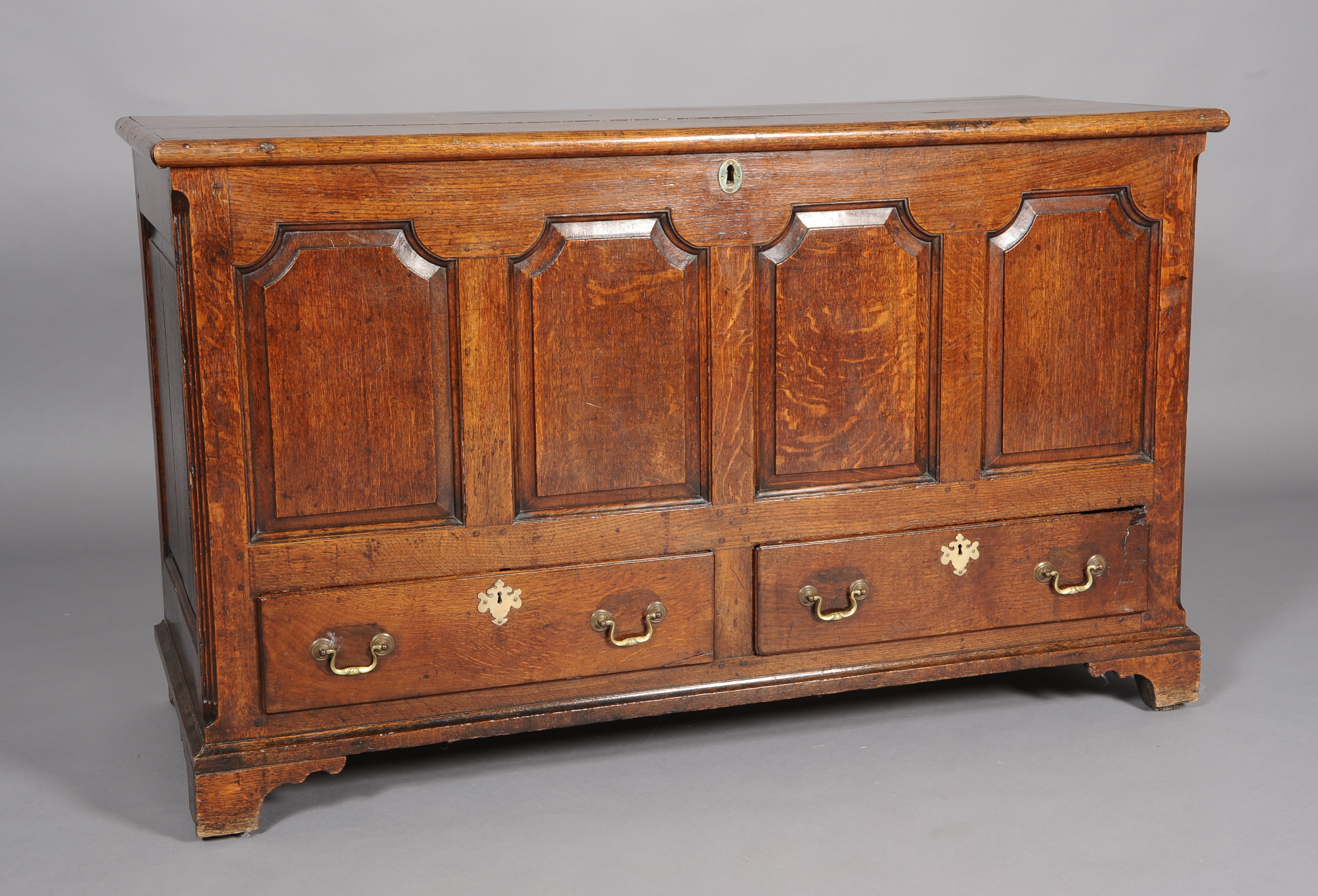 A MID 18TH CENTURY OAK MULE CHEST, having a planked top, above a quadruple ogee arch field-