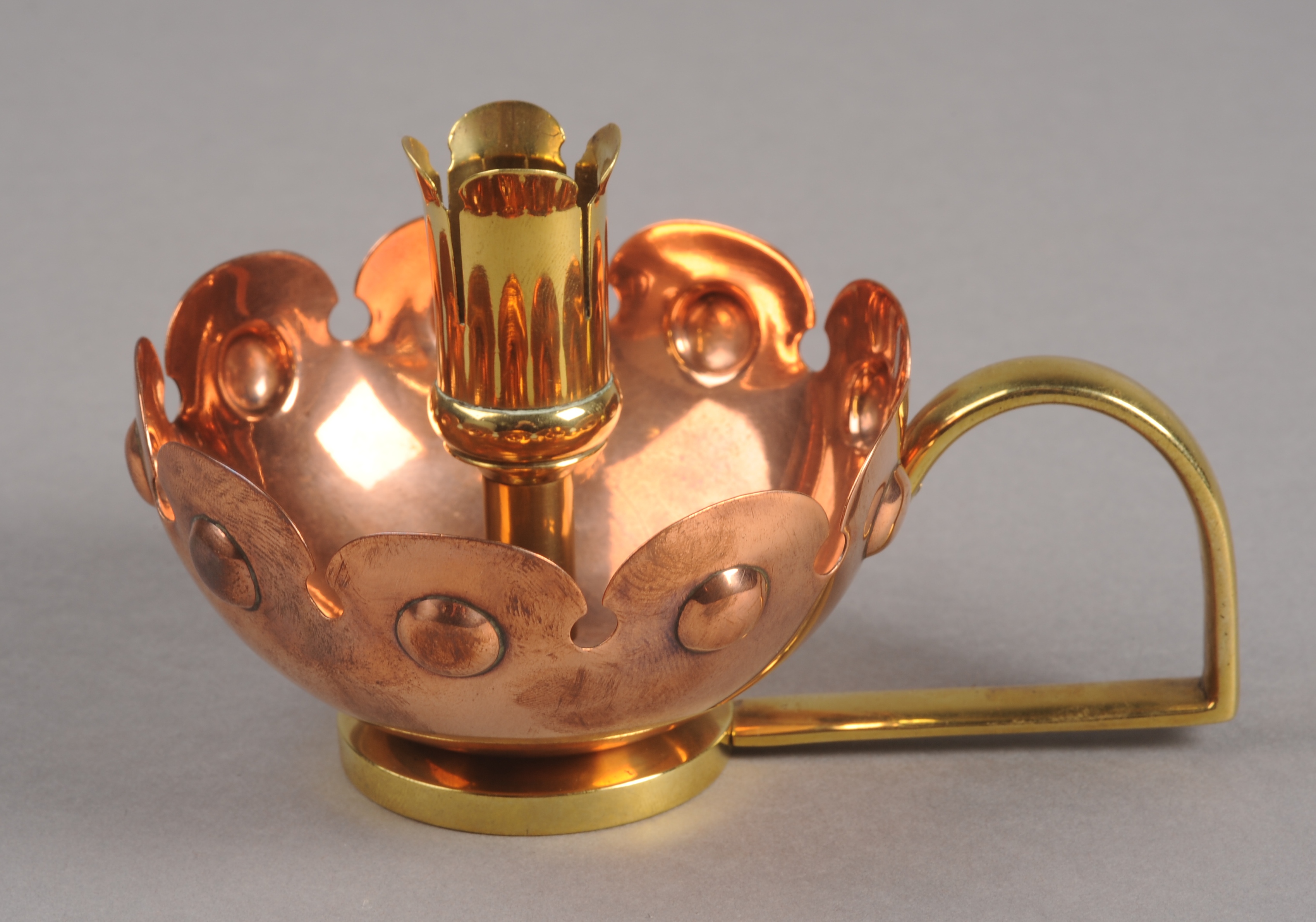 AN ARTS & CRAFTS BRASS AND COPPER CHAMBERSTICK, designed by William Arthur Smith Benson, in the