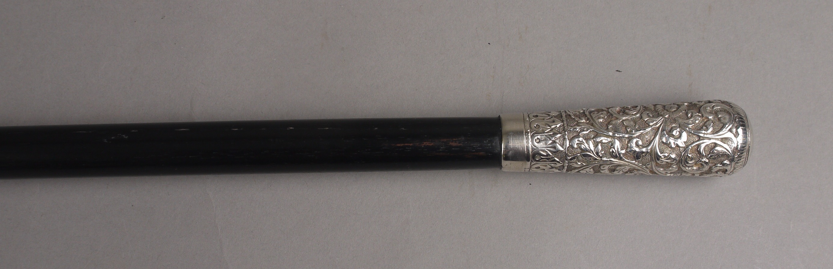 AN EDWARD VII EBONISED WALKING CANE, with a silver mount, chased with flowers and foliate scrolls,