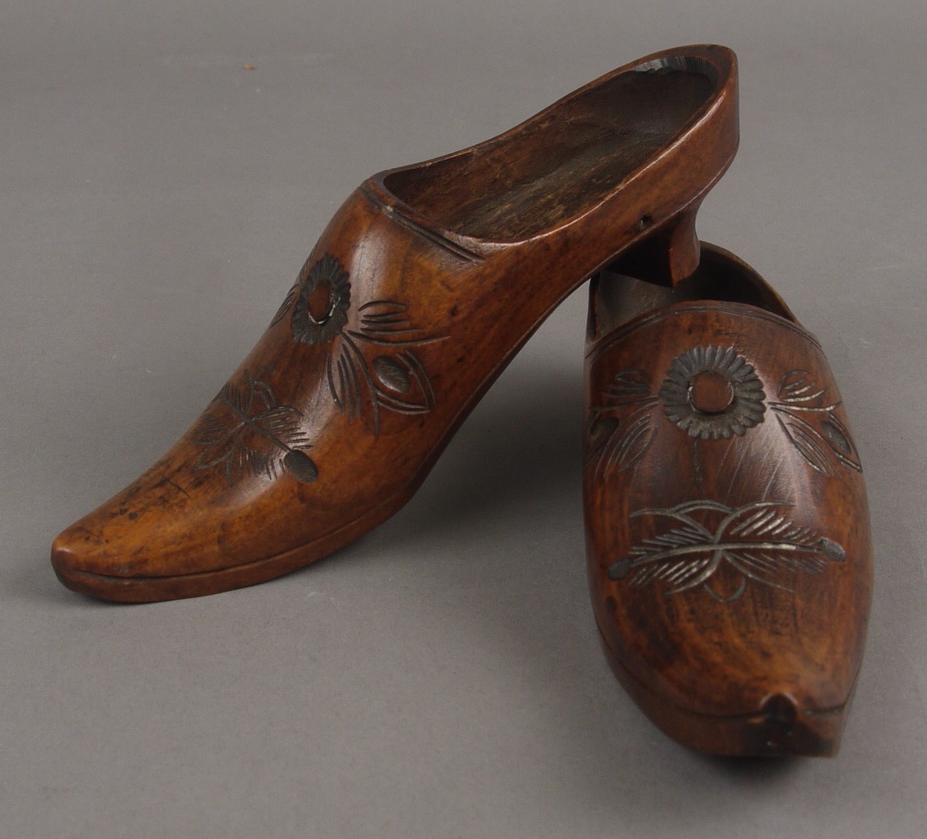A PAIR OF 19TH CENTURY FRUITWOOD CLOGS, the elongated fronts carved with flowers and leaves, 14cm