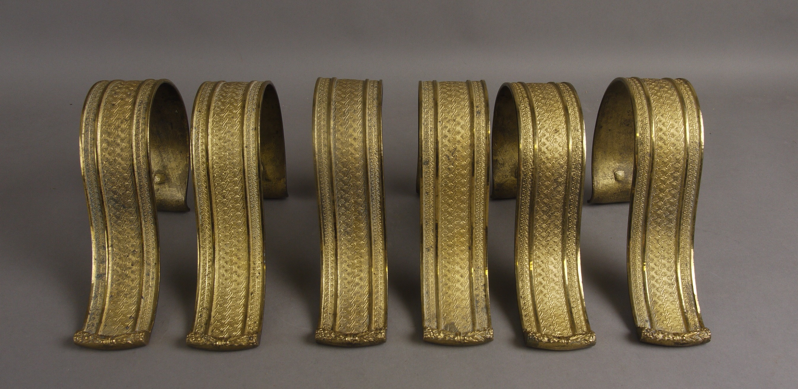 A SET OF SIX FRENCH GILT METAL CURTAIN TIE BACKS, of S scroll outline, cast in low relief with