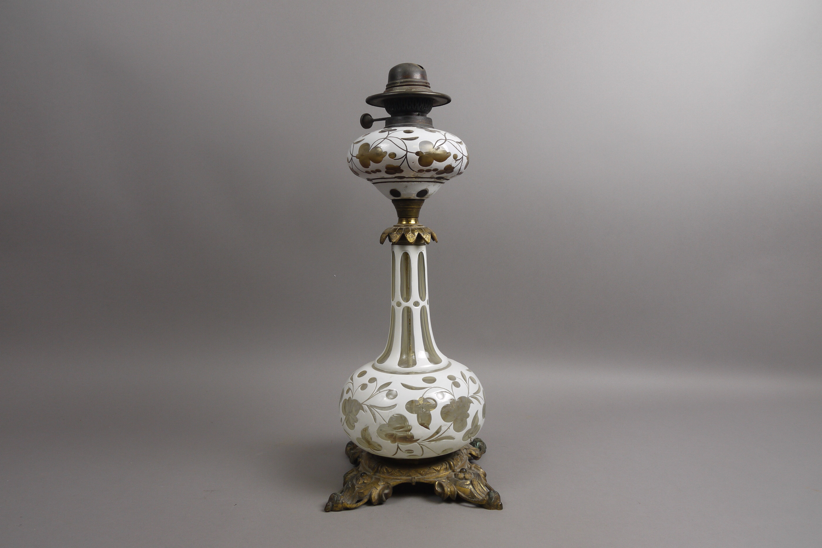 A VICTORIAN BRASS MOUNTED OVERLAY GLASS OIL LAMP, the clear glass overlaid in white and cut with