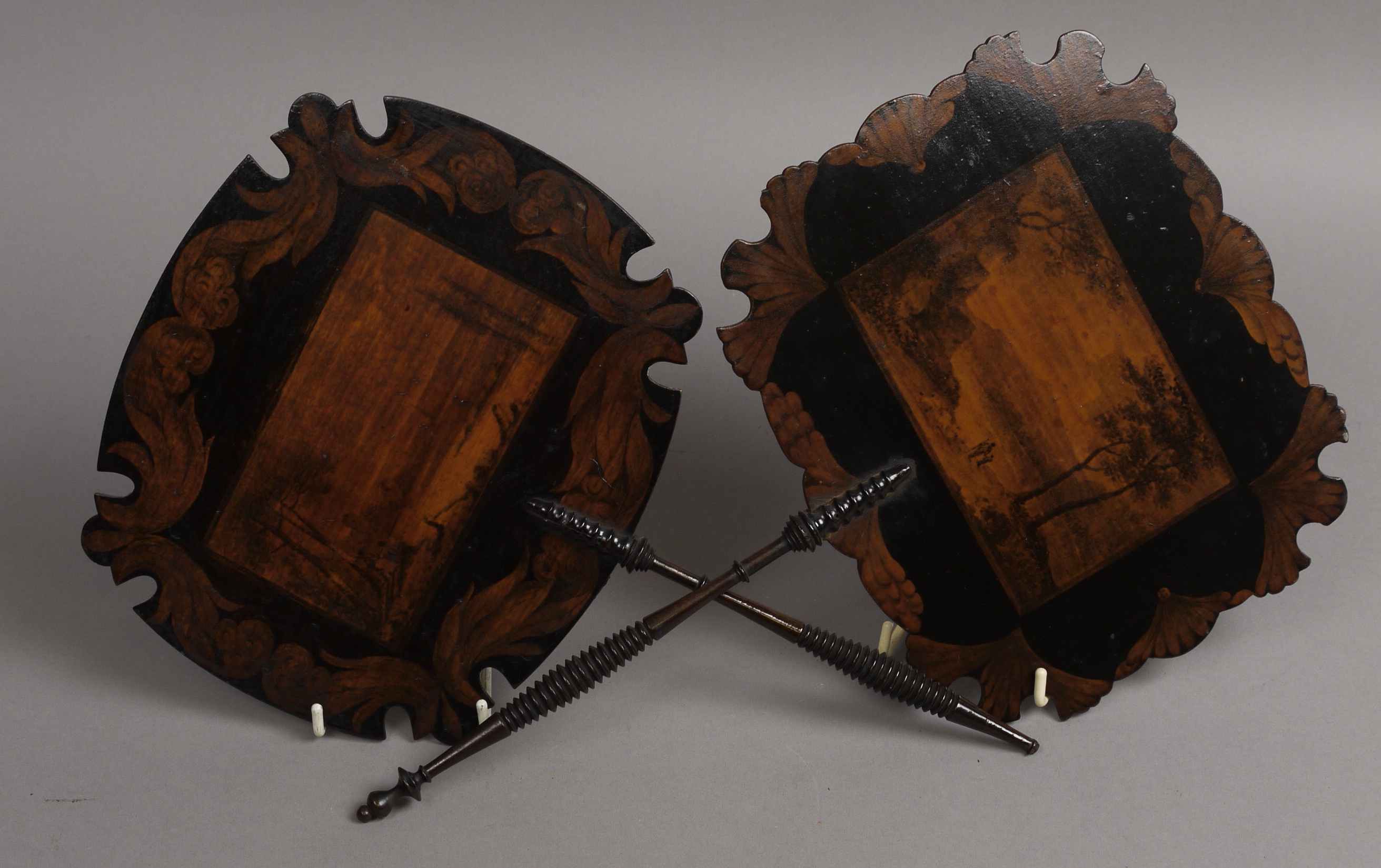 A PAIR OF REGENCY FACE SCREENS, the stained cartouche shape panels painted in black with landscapes,