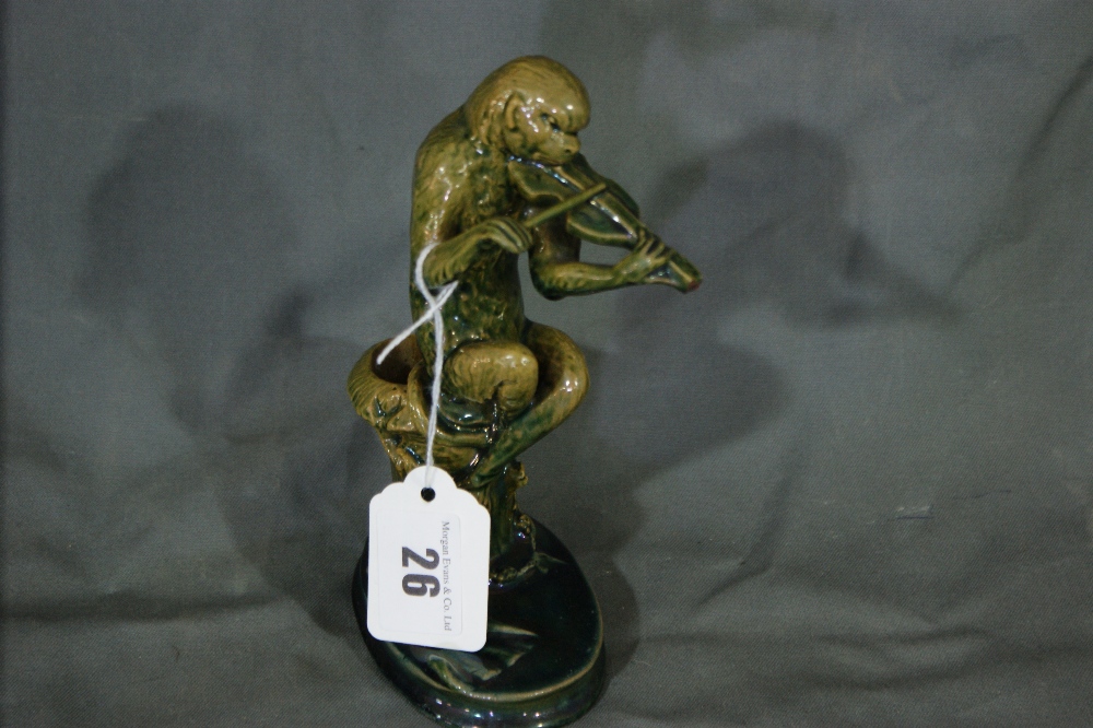 A Green Lustre Glazed Pottery Model Of A Seated Monkey Violinist, Minor Damage