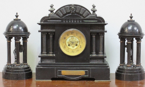 A Victorian black slate mantel clock garniture, of clock and two domed plinths, of classical