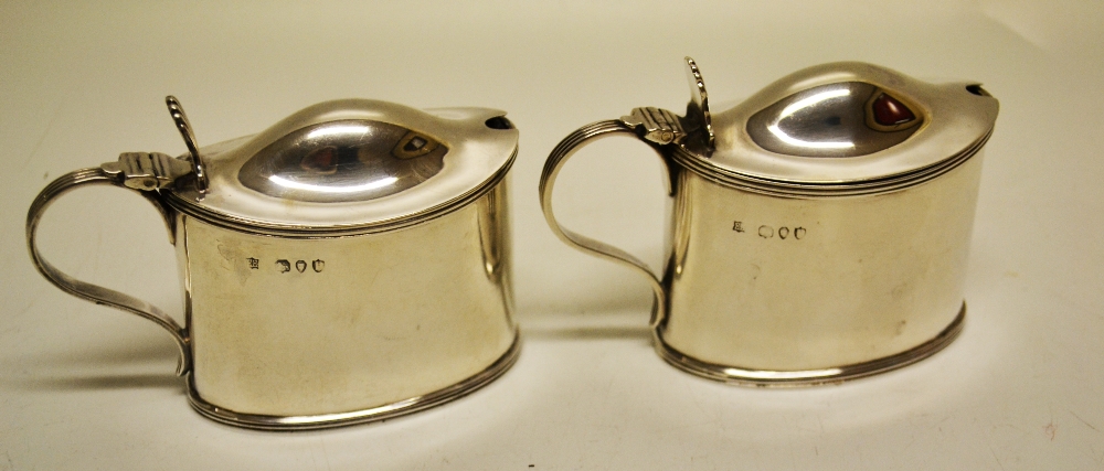 A pair of late Victorian oval silver mustard pots, with domed hinged covers having reeded