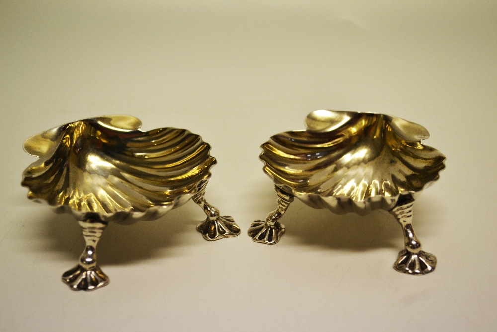 A pair of George II silver scallop shell salts, gilded interiors, on cast ribbed scroll legs to