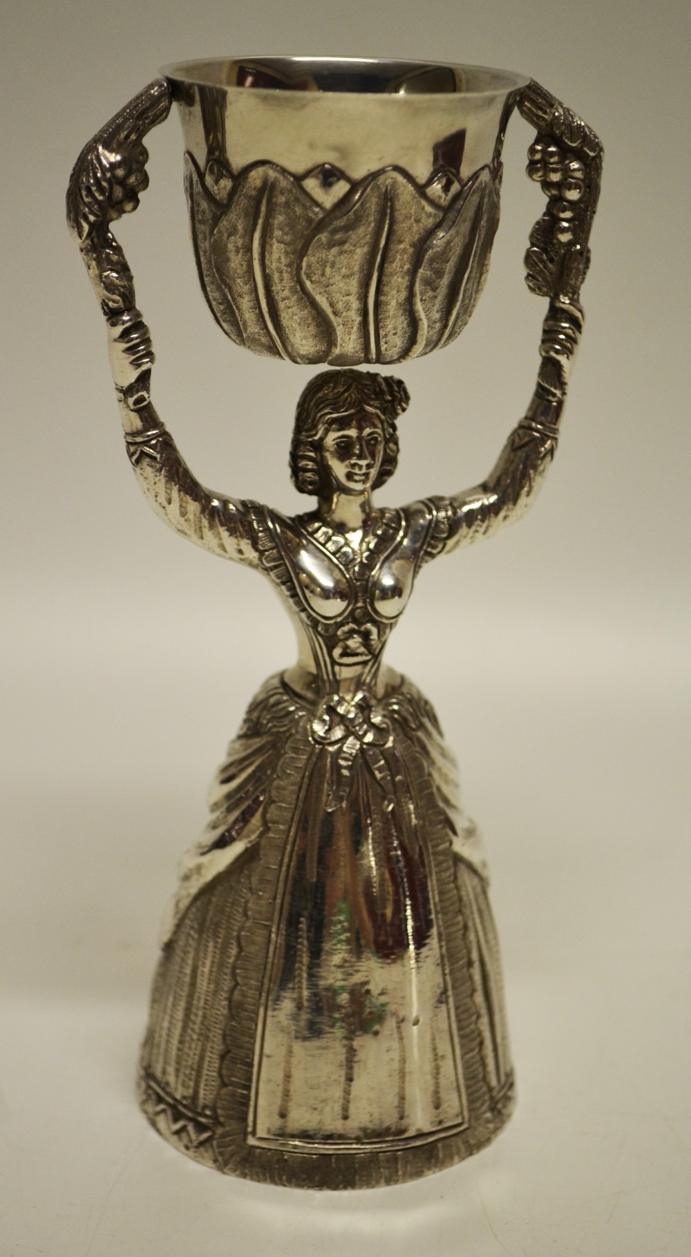 A cast silver copy of a seventeenth century wager cup, of a maid holding up a cup, swinging on