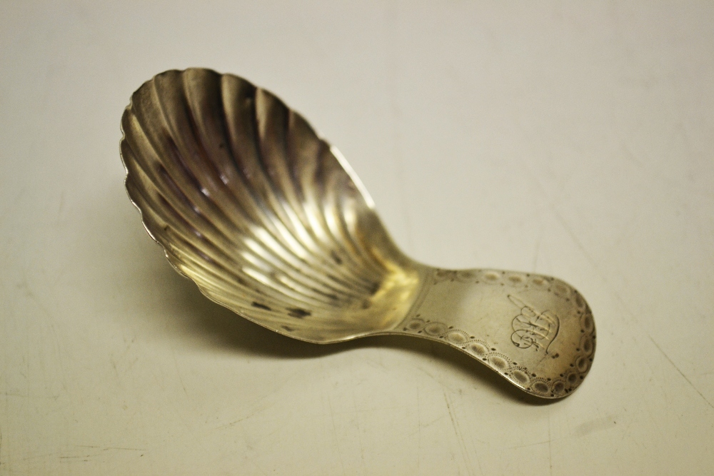 A George III silver caddy spoon, the bright cut handle engraved initials, having a shell fluted