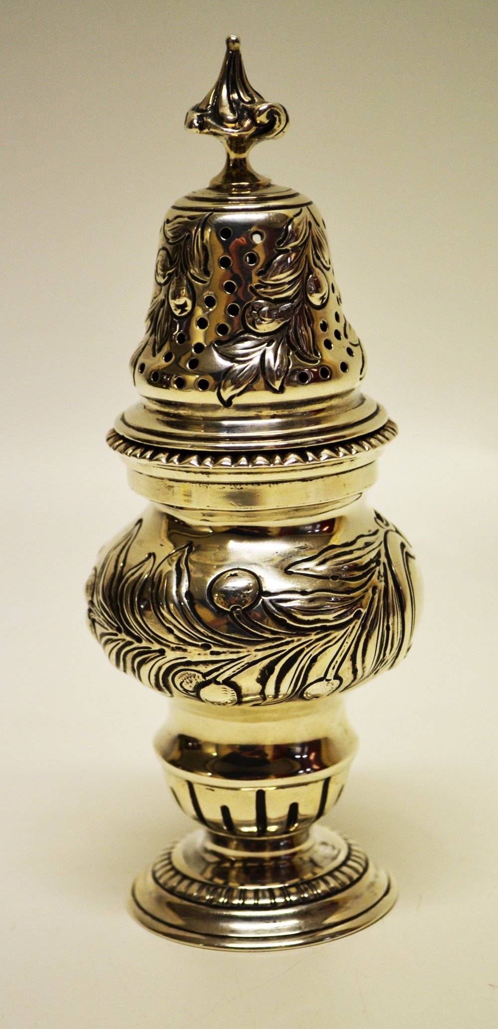 An Edwardian silver sugar caster, the baluster body with repoussé fruiting foliage and a vacant