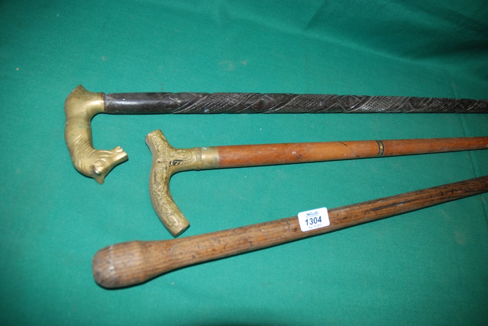 Three Walking Sticks, two with brass handles and one having carved detail.