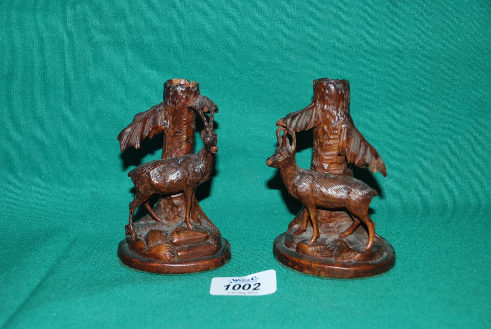 A pair of finely carved Black Forest Candlesticks and Candles decorated with goats stood under trees