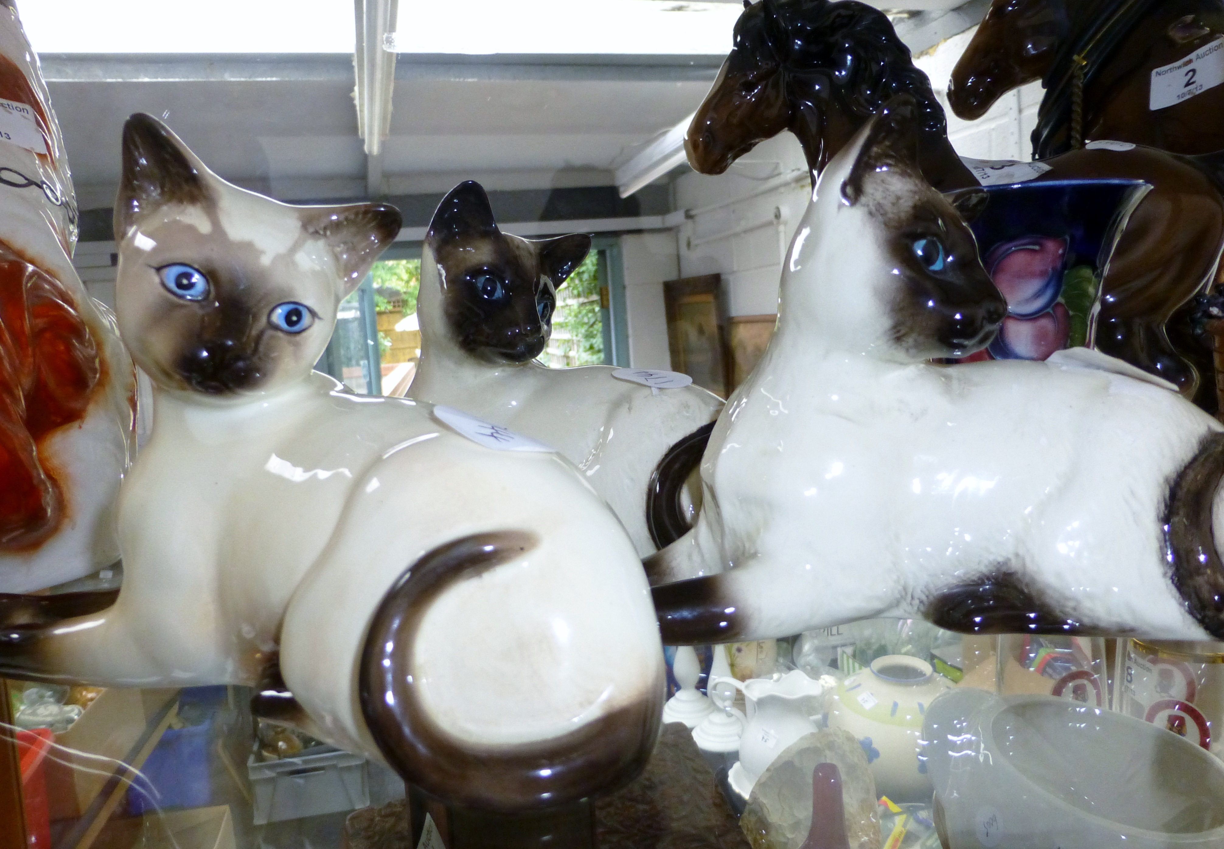 Three Beswick reclining Siamese cats